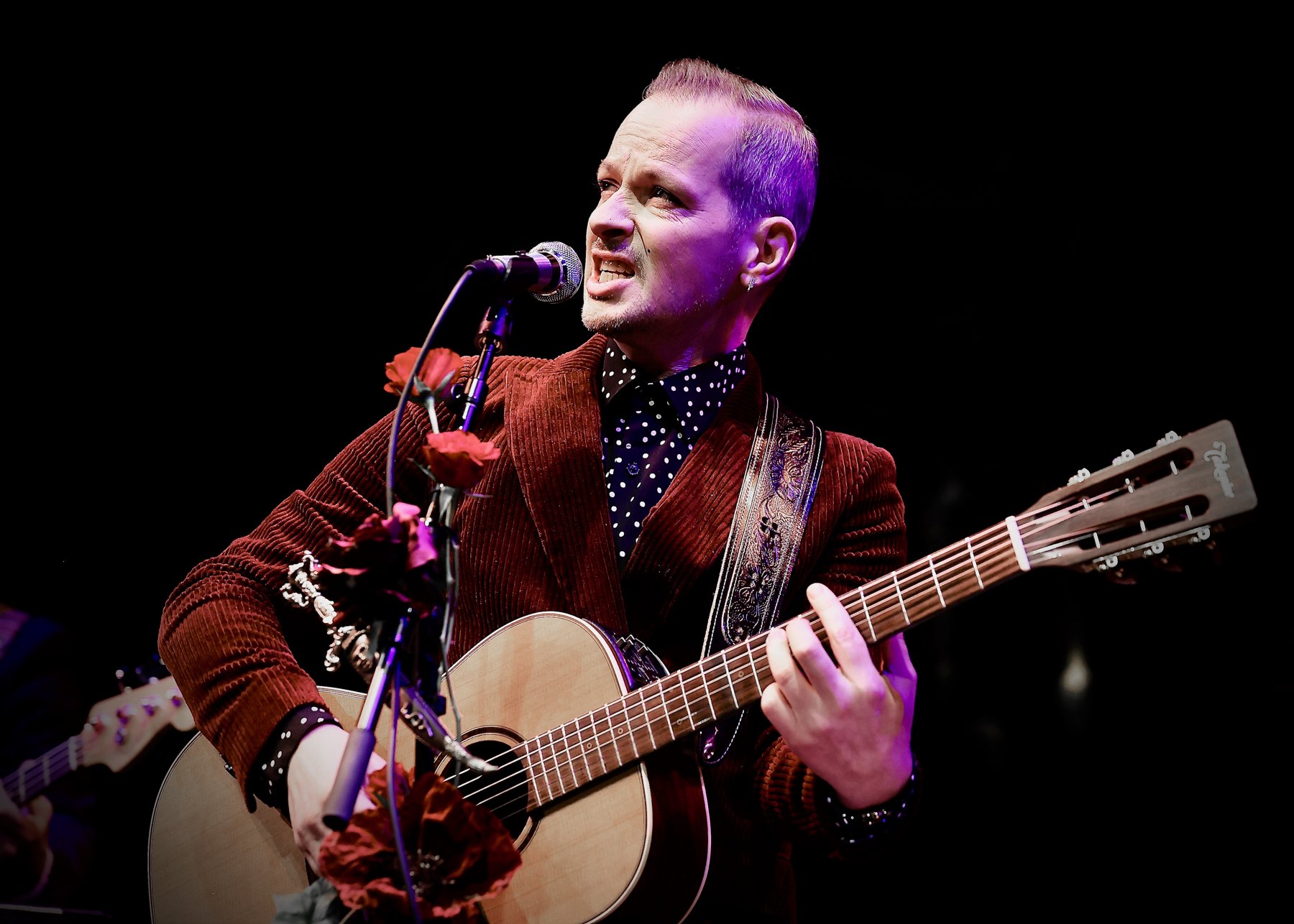 Denis Fischer singt mit Gitarre auf der Bühne